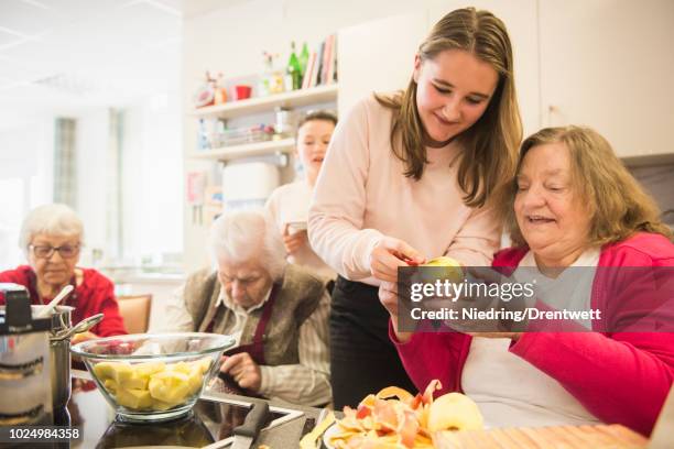 senior woman with girl cutting apple at rest home - retirement community stock pictures, royalty-free photos & images