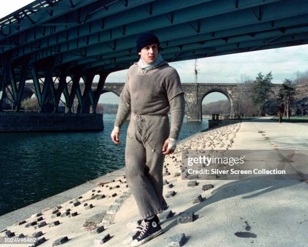 American actor Sylvester Stallone as Rocky Balboa, during the filming of the training montage for the boxing film 'Rocky', 1976. He is standing by...