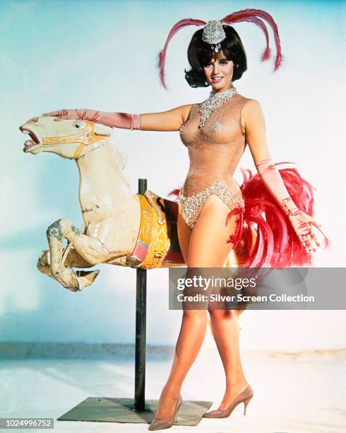 Actress Claudia Cardinale as Vicky Vicenti wearing a diaphanous outfit next to a carousel horse in a publicity still for the film 'Blindfold', 1966.