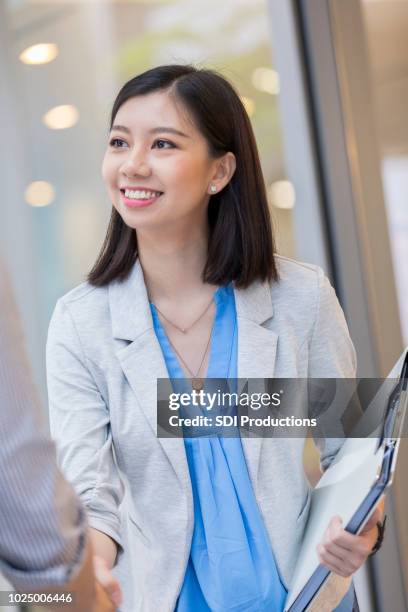 cheerful asian businesswoman greets client - case manager stock pictures, royalty-free photos & images