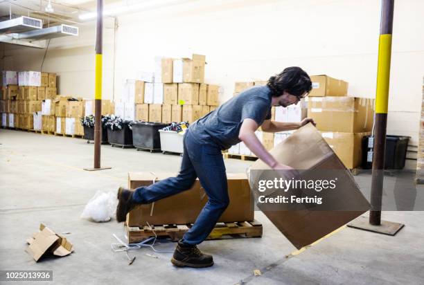a worker in a warehouse tripping over a broken pallet - stumble stock pictures, royalty-free photos & images