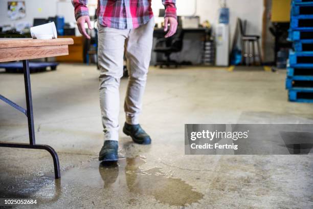 ein arbeiter in einem lagerhaus wandern in verschüttete flüssigkeit. - arbeitsstiefel stock-fotos und bilder