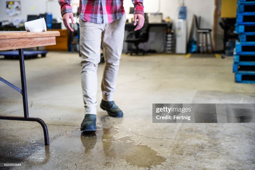 A worker in a warehouse walking in spilled liquid.