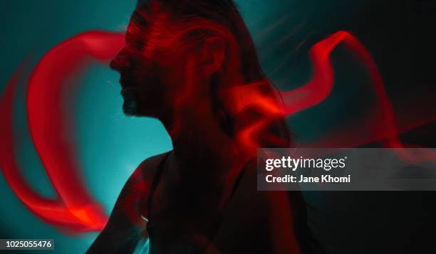 silhouette of young woman with light painting trails - luce fluorescente foto e immagini stock