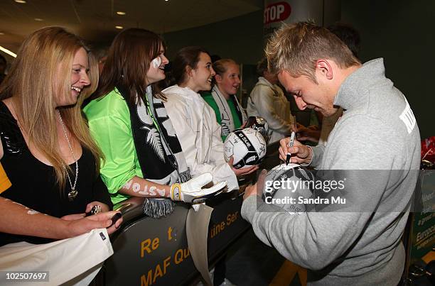 David Mulligan of the New Zealand All Whites signs autographs as they arrive home from the 2010 World Cup at the Auckland International Airport on...