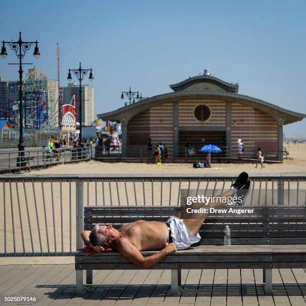 Man rests along the Coney Island boardwalk on a hot afternoon, August 29, 2018 in the Brooklyn borough of New York City. The New York City area is...