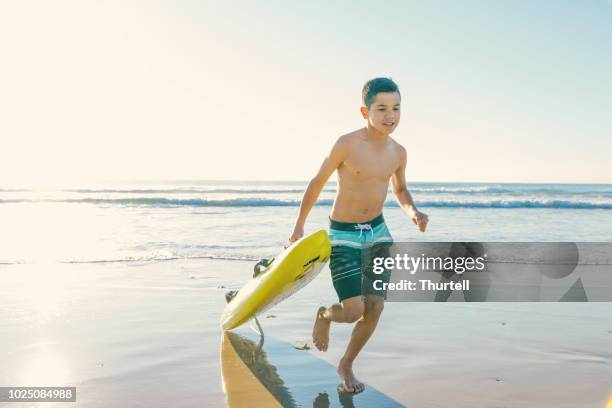 australian aboriginal boy at beach with surf rescue board - surf rescue stock pictures, royalty-free photos & images