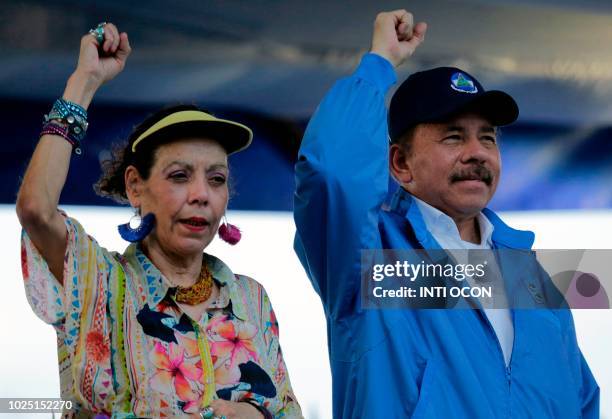 Nicaraguan President Daniel Ortega and his wife, Vice-President Rosario Murillo, raise their fists during the commemoration of the 51st anniversary...