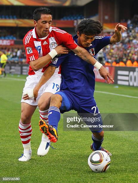 Lucas Barrios of Paraguay tackles Yuji Nakazawa of Japan during the 2010 FIFA World Cup South Africa Round of Sixteen match between Paraguay and...