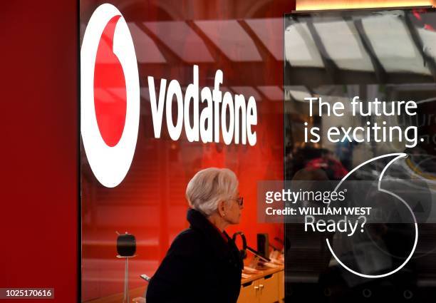 Woman walks past a Vodafone store in Melbourne on August 30, 2018. - Vodafone Hutchison Australia and TPG Telecom announced plans on August 30 to...