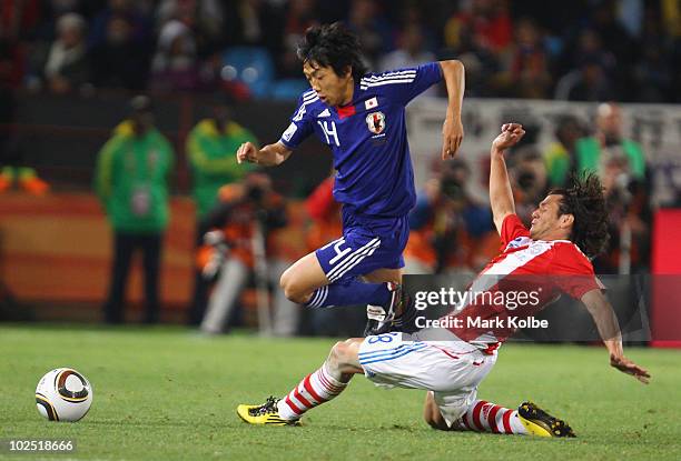 Kengo Nakamura of Japan is tackled by Nelson Valdez of Paraguay during the 2010 FIFA World Cup South Africa Round of Sixteen match between Paraguay...