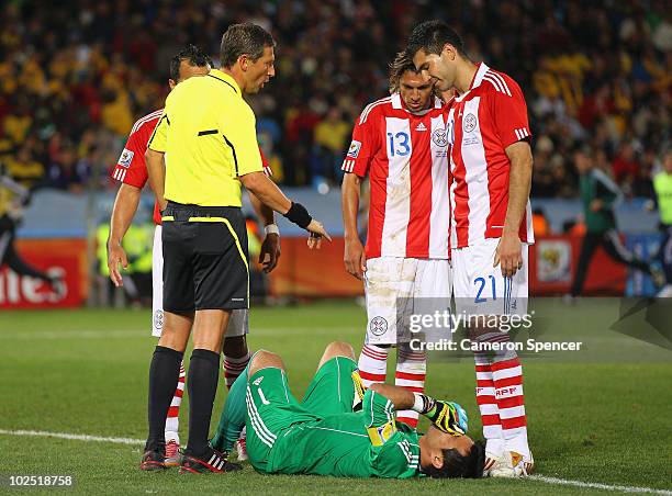 Justo Villar of Paraguay lies on the pitch injured as referee Frank de Bleeckere speaks to Antolin Alcaraz during the 2010 FIFA World Cup South...