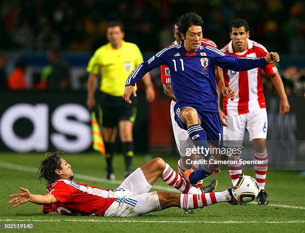 Enrique Vera of Paraguay tackles Keiji Tamada of Japan during the 2010 FIFA World Cup South Africa Round of Sixteen match between Paraguay and Japan...