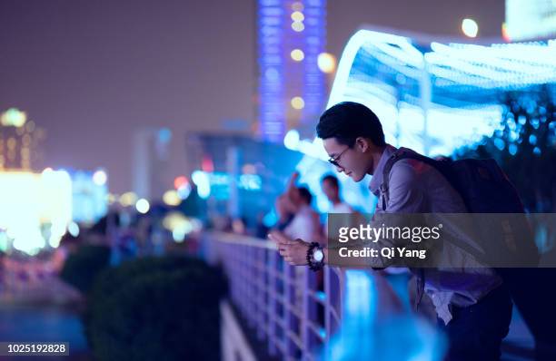 young businessman looking at smartphone, shanghai, china - corporate travel photos et images de collection
