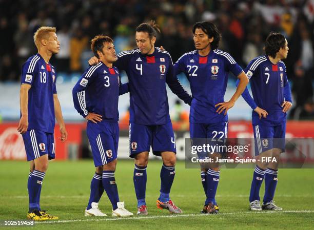 Keisuke Honda of Japan stands with Yuichi Komano of Japan as Komano is comforted by teammates Marcus Tulio Tanaka and Yuji Nakazawa after missing a...