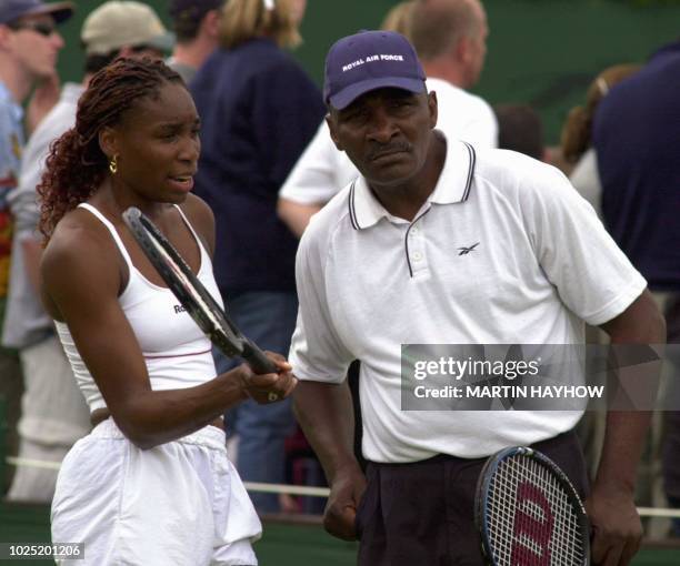 Player Venus Williams and her father and coach Richard Williams discuss a point 01 July 2000 during a training session with Venus' sister Serena...