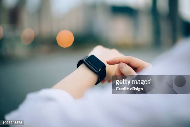 close up of businesswoman checking her smartwatch in downtown city - orologio da polso foto e immagini stock