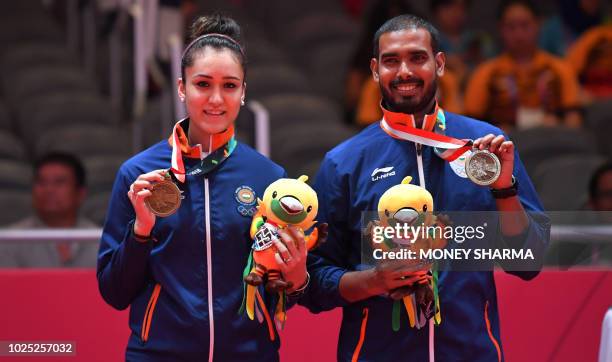 Bronze medallist India's Manika Batra and Sharath Kamal Achanta celebrate on the podium during the victory ceremony for the table tennis mixed...