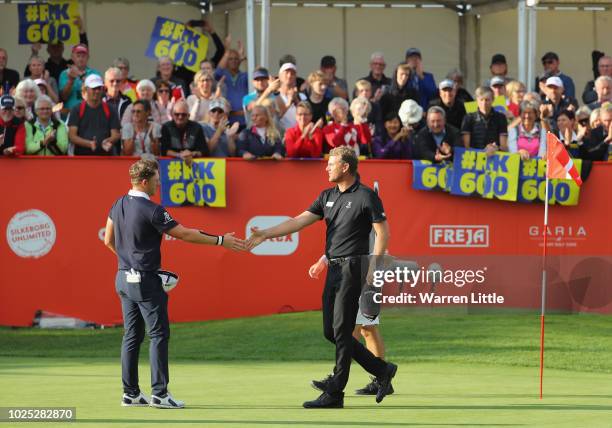 Robert Karlsson of Sweden shakes hands on the 18th green as the crowd hold up signs recognising his 600th appearence on tour during day one of the...