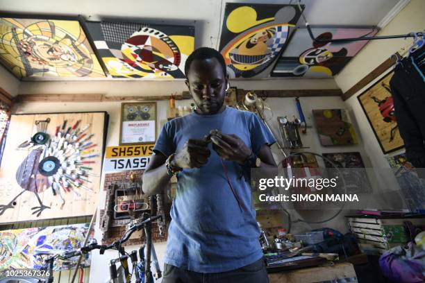 Kenyan "junk artist" Evans Ngure stands in his workshop as he creates objects made with collected materials in Nairobi on August 2, 2018. - In a room...