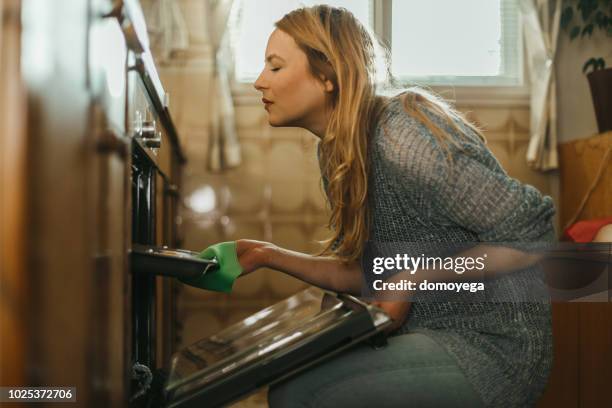 junge frau backt gebäck in der küche zu hause - backofen stock-fotos und bilder