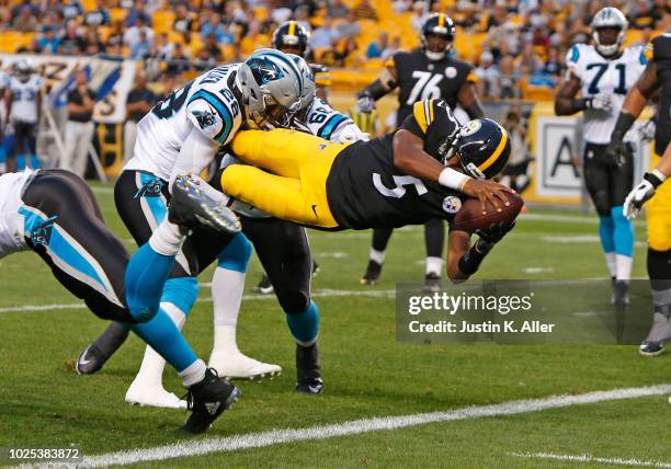 Joshua Dobbs of the Pittsburgh Steelers dives over Rashaan Gaulden and Daeshon Hall of the Carolina Panthers scoring a 3 yard touchdown run in the...