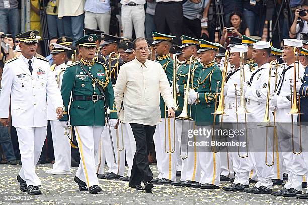 Benigno Aquino, Philippine president, right, walks past an honor guard following his inaugural speech at Quirino Grandstand in Manila, the...