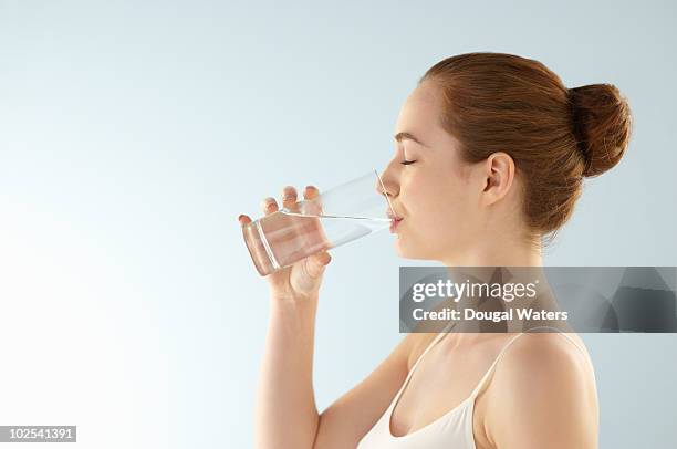 young woman drinking glass of water. - consume photos et images de collection