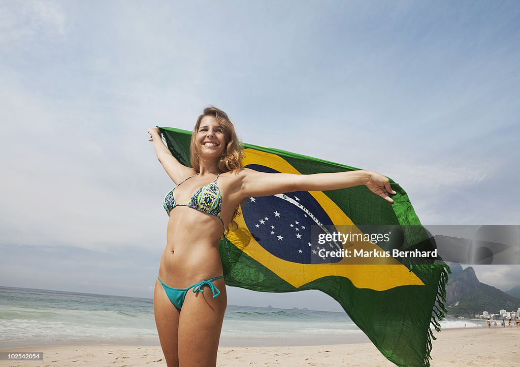 Woman holding Brazil flag at Ipanema beach