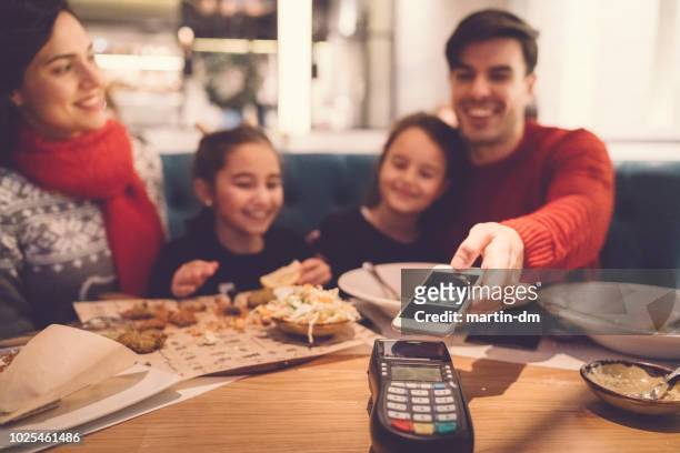family in restaurant paying contactless - paying for dinner imagens e fotografias de stock