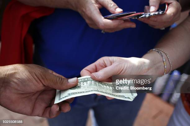 An attendee exchanges a U.S. Twenty dollar banknote for buttons outside a rally with U.S. President Donald Trump in Evansville, Indiana, U.S., on...
