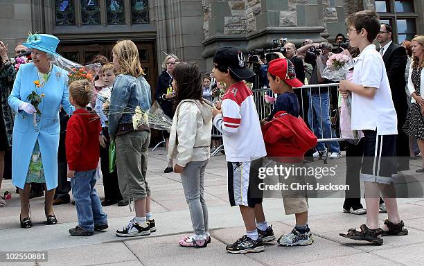 Queen Elizabeth II is given flowers by children as she visits the Canadian Museum of Nature on June 30, 2010 in Ottawa, Canada. The Queen and Duke of...