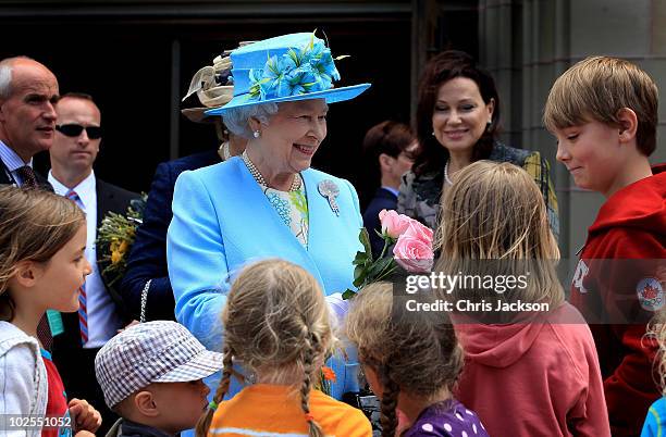 Queen Elizabeth II is given flowers by children as she visits the Canadian Museum of Nature on June 30, 2010 in Ottawa, Canada. The Queen and Duke of...