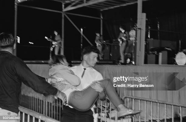 Fan is carried away at a concert by The Beatles at the Empire Stadium, Vancouver, 22nd August 1964.