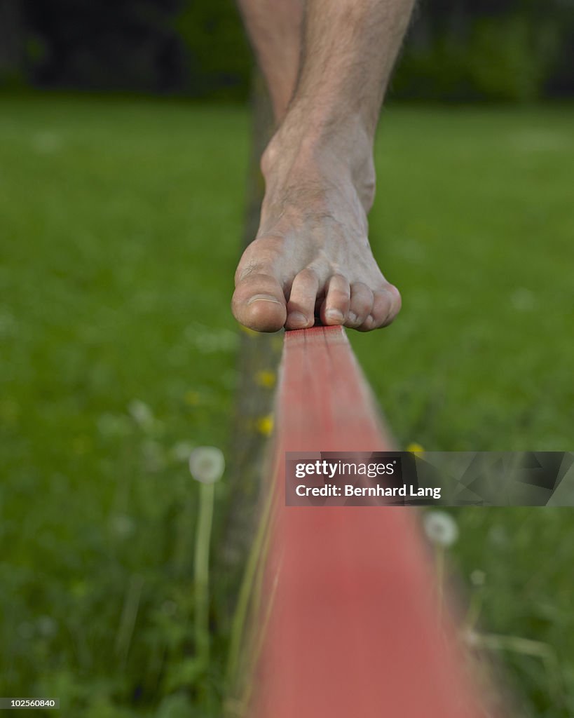 Man's bare feet balancing on a slackline