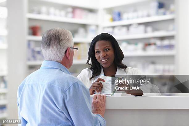 pharmacist explaining pamphlet to senior - pharmacist explaining stock pictures, royalty-free photos & images