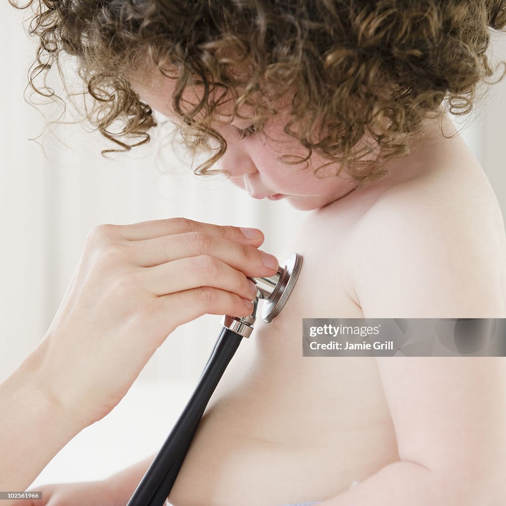 Toddler looking at stethoscope during medical exam