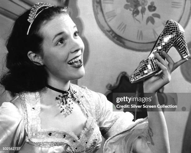 English actress Julie Andrews poses with a glass slipper in the role of Cinderella, circa 1957. She played the fairytale character in a film...