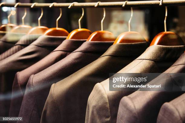 men suits hanging on a rack, close up - schneider stock-fotos und bilder