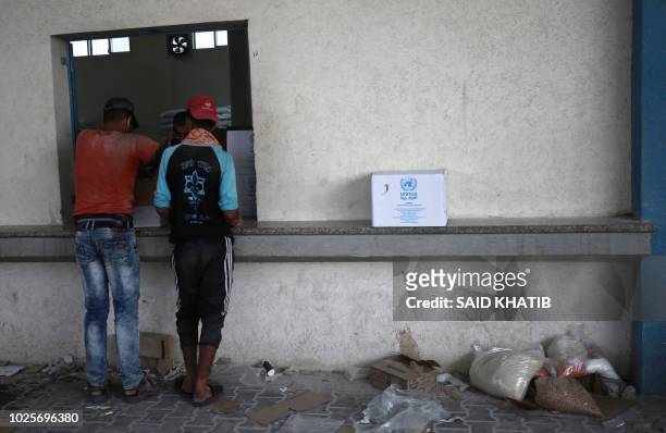 Palestinian men collect aid food at a United Nations' compound in the Rafah refugee camp in the southern Gaza Strip on September 1, 2018. The United...
