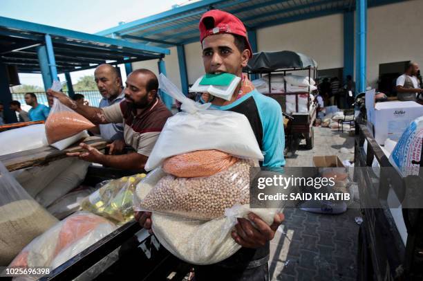 Palestinian men collect aid food at a United Nations' compound in the Rafah refugee camp in the southern Gaza Strip on September 1, 2018. The United...