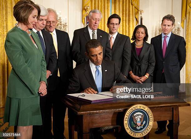 President Barack Obama, surrounded by members of Congress and his administration, signs the Iran Sanctions Bill in the East Room of the White House...