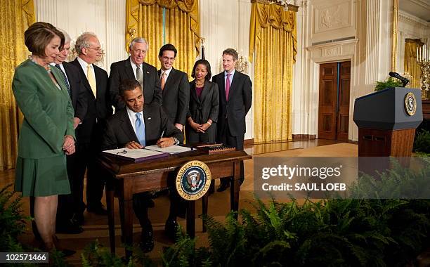 President Barack Obama, surrounded by members of Congress and his administration, signs the Iran Sanctions Bill in the East Room of the White House...