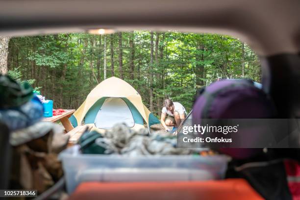 man unloading the car trunk packed with luggage and other items for road trip and camping - car camping luggage imagens e fotografias de stock