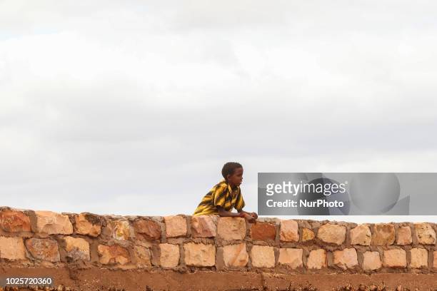August 2018 - A Kenyan child stands on the wall of a humanitarian organization watching poor people standing for humanitarian aid from a humanitarian...