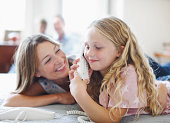 Mother and daughter (6-7) talking on telephone
