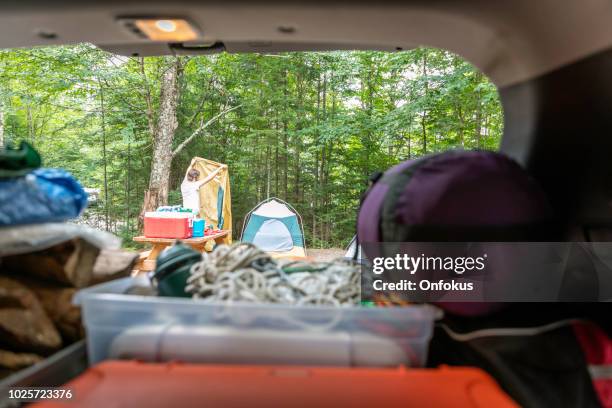 homme de déchargement du coffre de la voiture rempli de bagages et autres objets pour le voyage sur la route et de camping - car camping luggage photos et images de collection