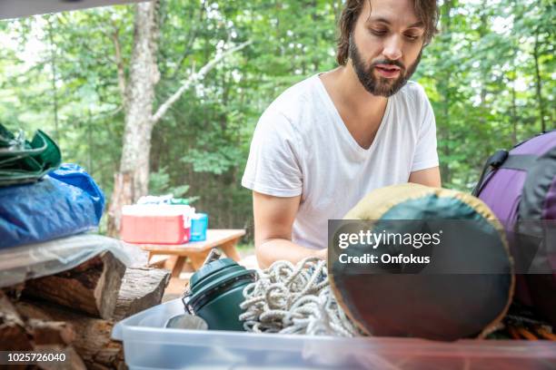 homme de déchargement du coffre de la voiture rempli de bagages et autres objets pour le voyage sur la route et de camping - car camping luggage photos et images de collection