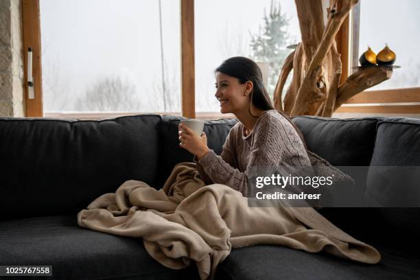 happy woman at home drinking a cup of coffee - winter sofa stock pictures, royalty-free photos & images