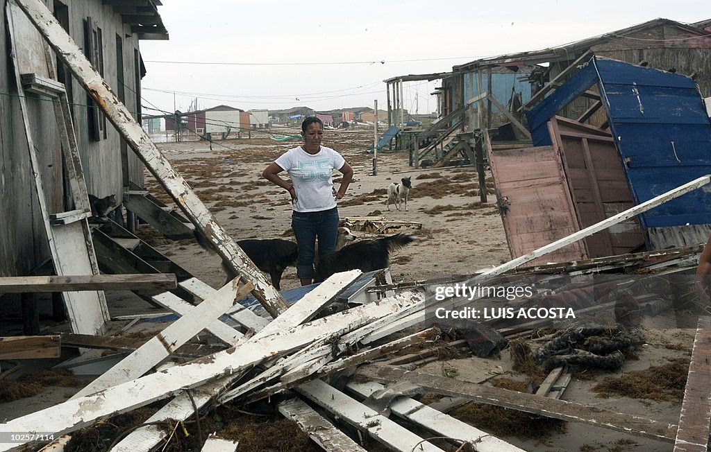 A woman stares at her damaged house afte